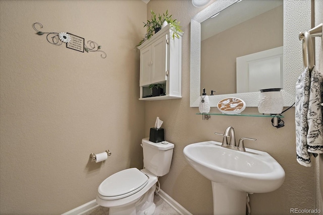 bathroom with a sink, baseboards, and toilet