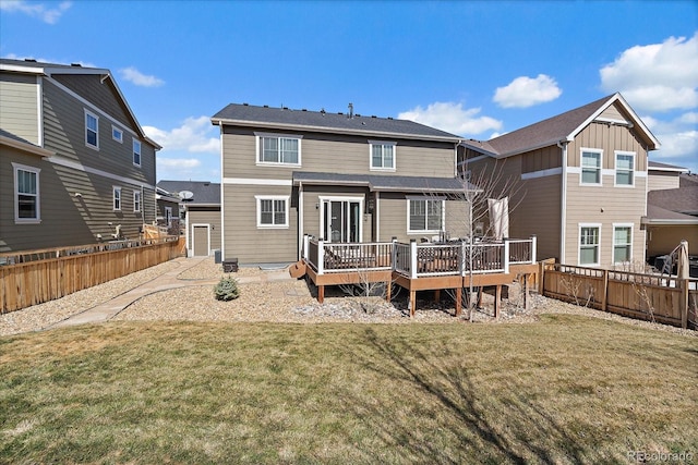 rear view of house with a deck, a yard, and fence