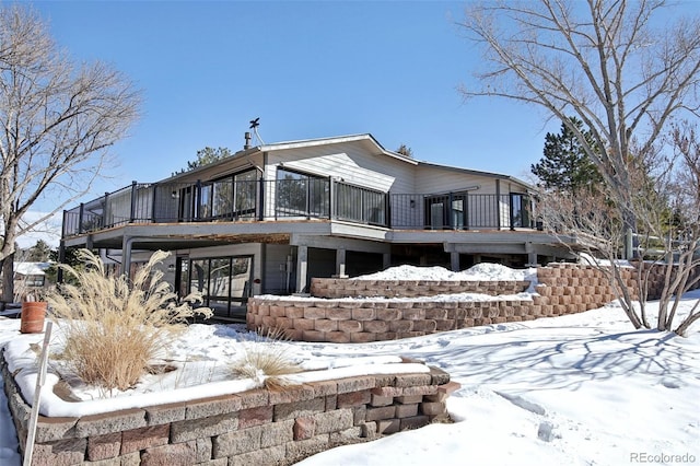 snow covered house featuring a wooden deck