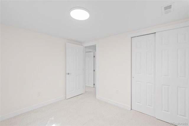 unfurnished bedroom with light colored carpet and a closet