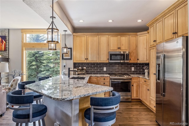 133 Creek Ln, Silverthorne, CO 80498 - kitchen featuring appliances with stainless steel finishes, a breakfast bar, dark wood-style flooring, decorative backsplash, and a peninsula