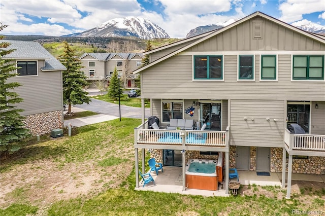 133 Creek Ln, Silverthorne, CO 80498 - rear view of property with a hot tub, a patio area, a mountain view, board and batten siding, and a lawn