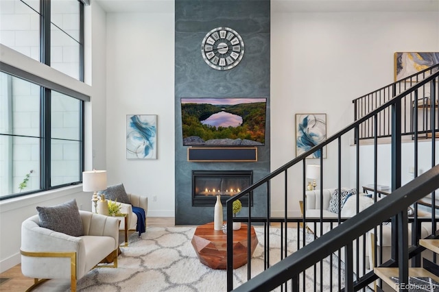 living room featuring a towering ceiling, hardwood / wood-style flooring, and a fireplace