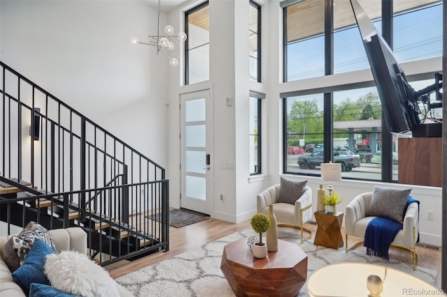 living room featuring a towering ceiling, light hardwood / wood-style flooring, and an inviting chandelier