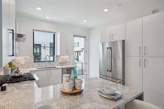 kitchen featuring white cabinets, high end refrigerator, range, backsplash, and sink