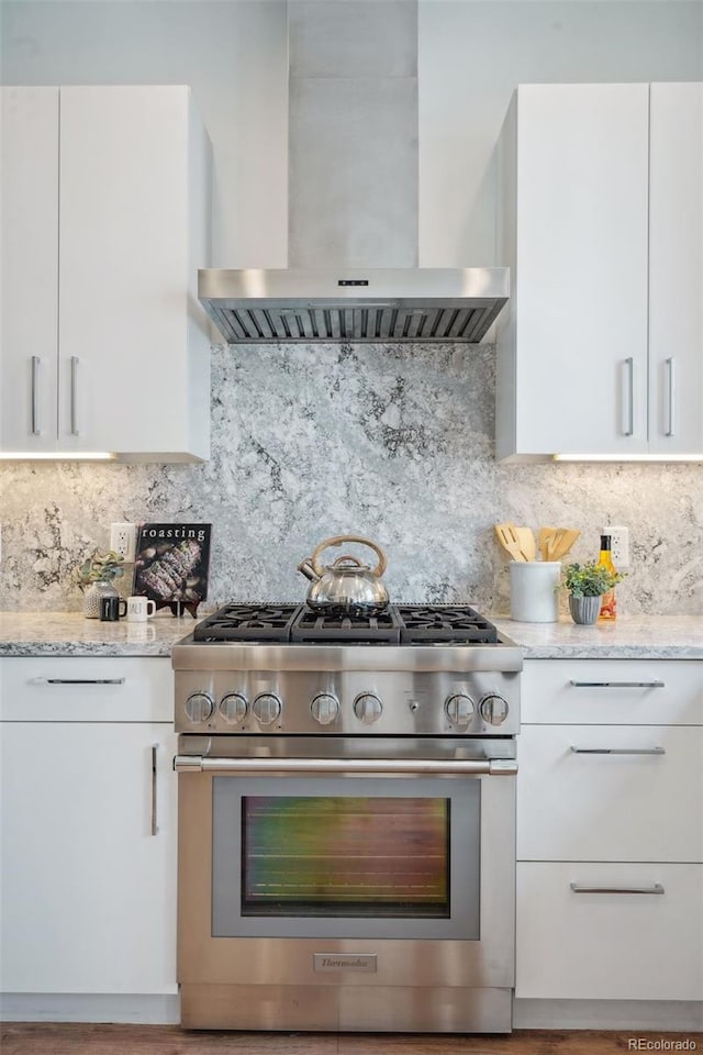 kitchen featuring wall chimney range hood, high end range, and backsplash