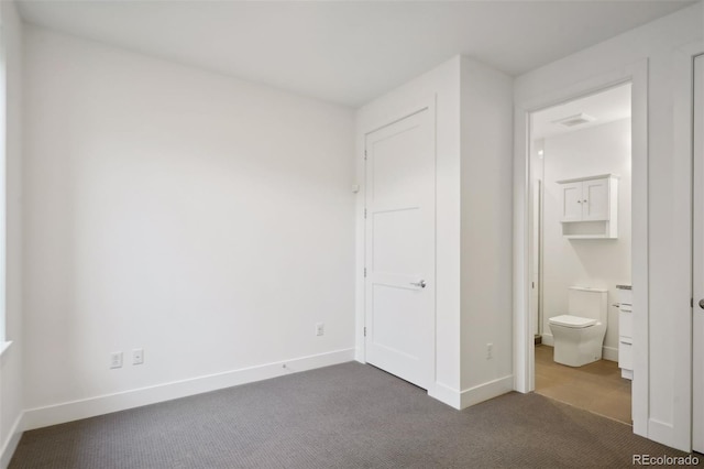 unfurnished bedroom featuring dark tile floors and ensuite bath