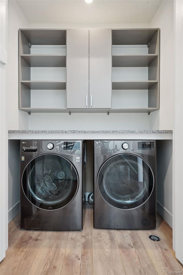 laundry room with washer and dryer and light hardwood / wood-style flooring