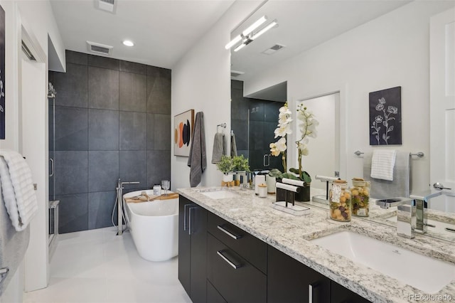 bathroom with tile floors, dual bowl vanity, a tub, and tile walls