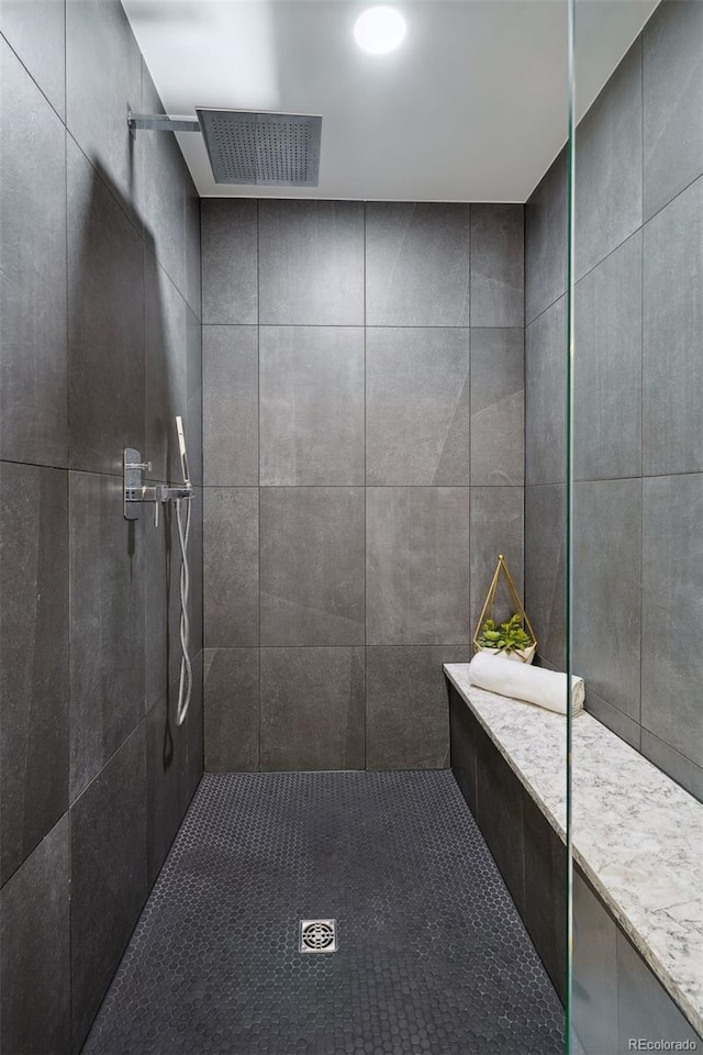 bathroom with tiled shower and tile walls