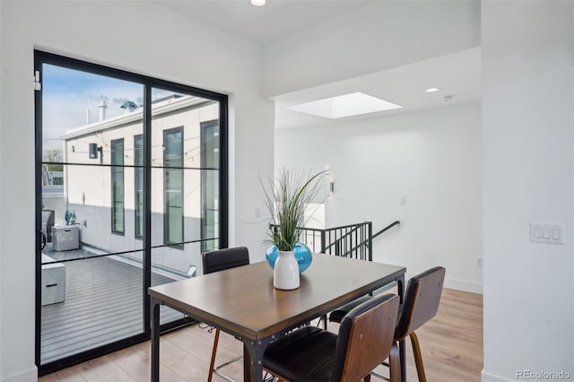 dining area with a skylight and light hardwood / wood-style flooring