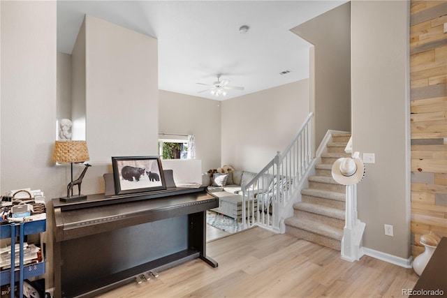 stairs with wood-type flooring and ceiling fan