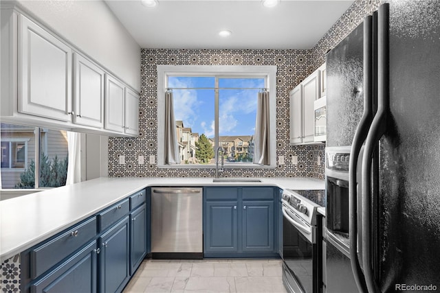 kitchen with blue cabinetry, stainless steel appliances, sink, and white cabinetry