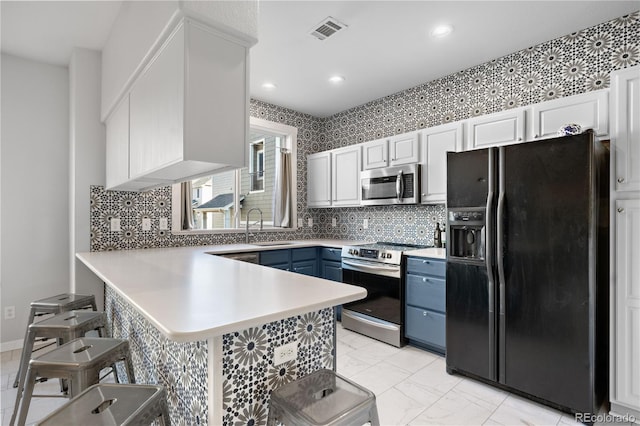 kitchen featuring white cabinetry, kitchen peninsula, a kitchen breakfast bar, stainless steel appliances, and blue cabinetry