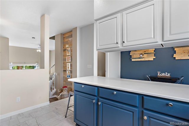 kitchen featuring a kitchen bar, ceiling fan, blue cabinetry, and white cabinets