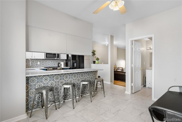 kitchen with black refrigerator with ice dispenser, white cabinetry, a breakfast bar area, and kitchen peninsula