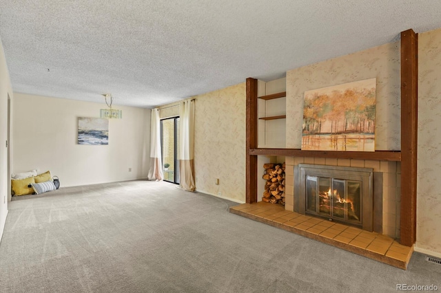 unfurnished living room with carpet flooring, a textured ceiling, and a tile fireplace