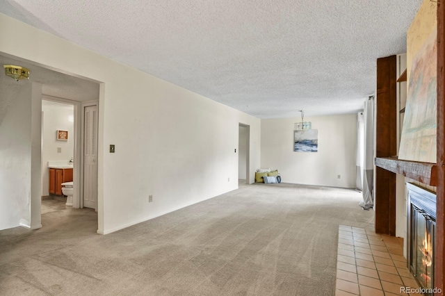 unfurnished living room featuring light carpet, sink, and a textured ceiling