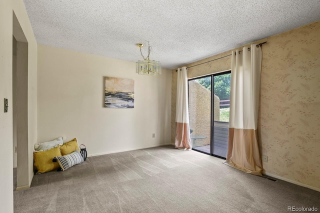 carpeted empty room featuring a textured ceiling and an inviting chandelier