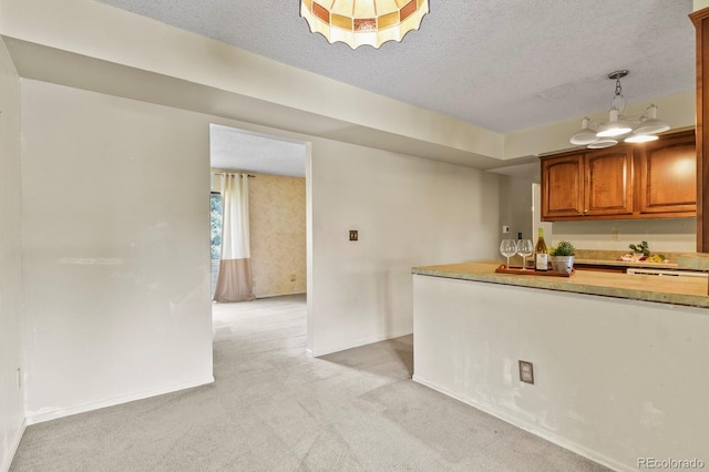 kitchen featuring a textured ceiling, light colored carpet, and hanging light fixtures