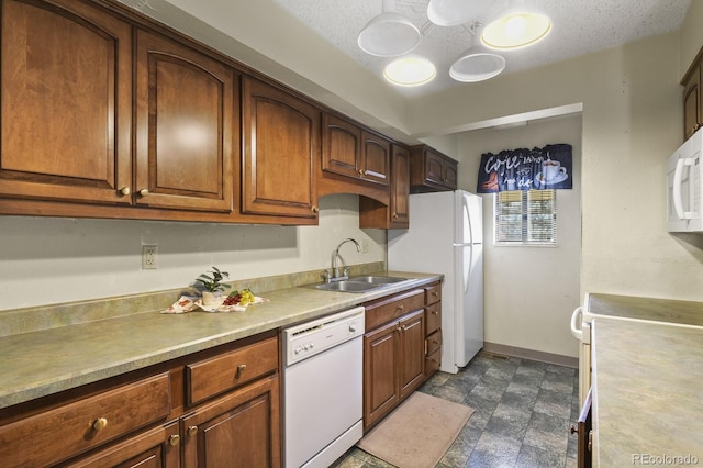 kitchen with a textured ceiling, sink, and white appliances