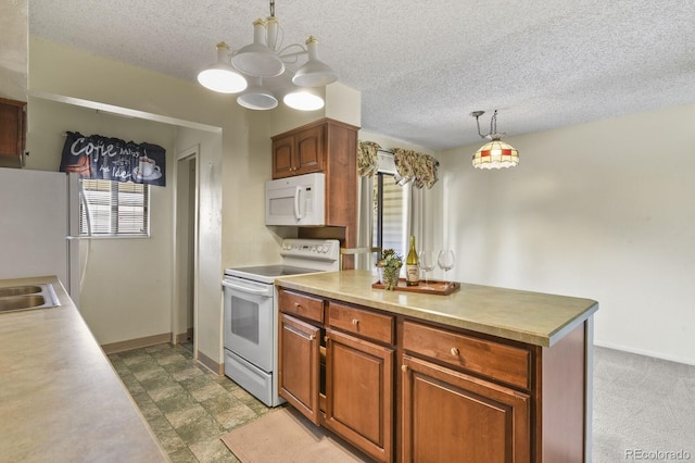 kitchen featuring a textured ceiling, a center island, hanging light fixtures, and white appliances