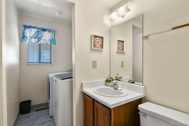 bathroom with vanity, toilet, and washing machine and dryer