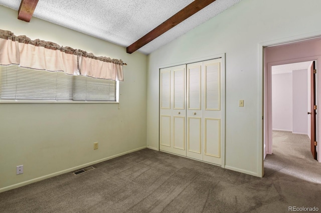 unfurnished bedroom with vaulted ceiling with beams, a closet, dark carpet, and a textured ceiling