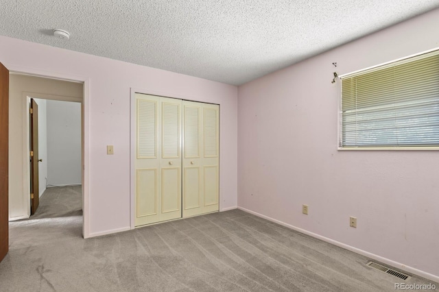 unfurnished bedroom with a textured ceiling, light carpet, and a closet