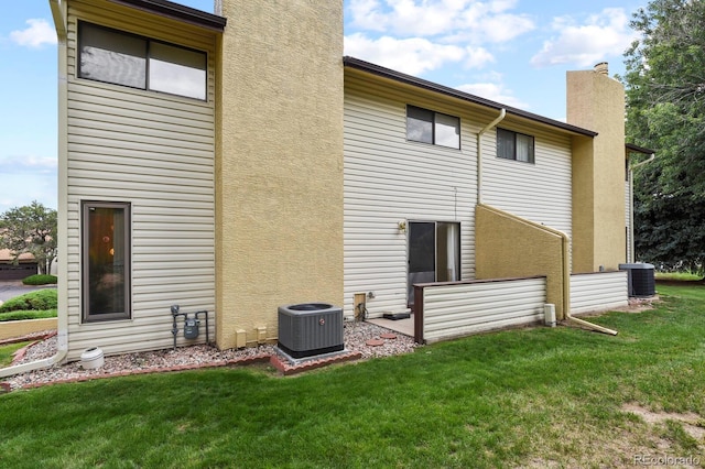 back of house with a lawn and central AC unit