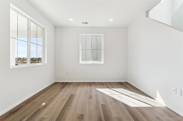 unfurnished room featuring recessed lighting, wood finished floors, visible vents, and baseboards