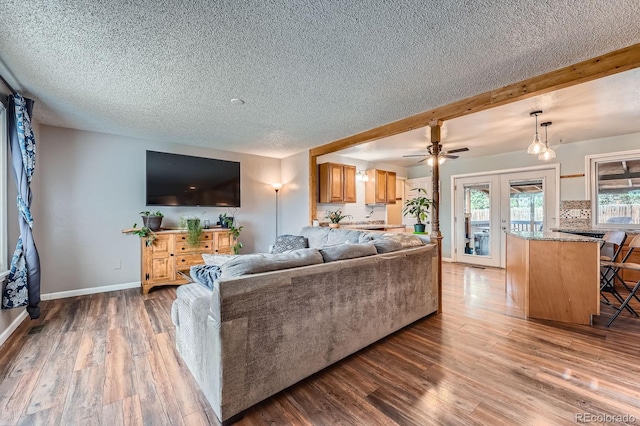 living room featuring french doors, a ceiling fan, a textured ceiling, wood finished floors, and baseboards