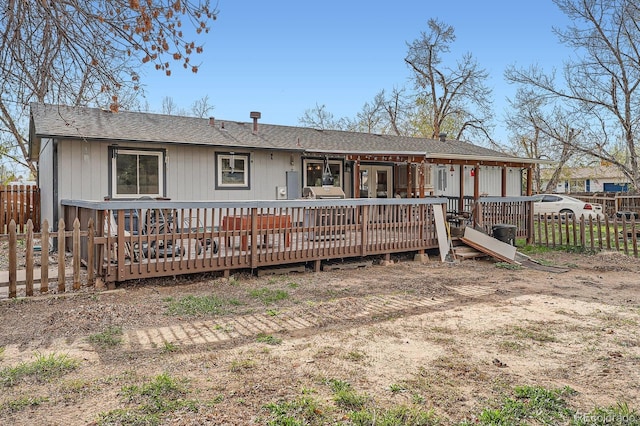 rear view of house featuring roof with shingles, fence, and a wooden deck