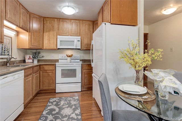 kitchen with white appliances, a sink, and light wood-style floors