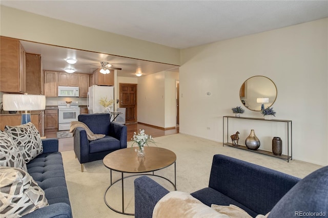 living area featuring light carpet, ceiling fan, and baseboards