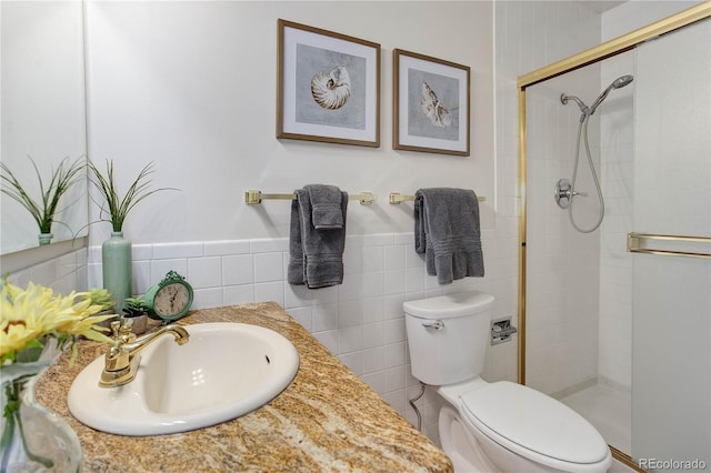 full bath with toilet, a stall shower, tile walls, vanity, and wainscoting