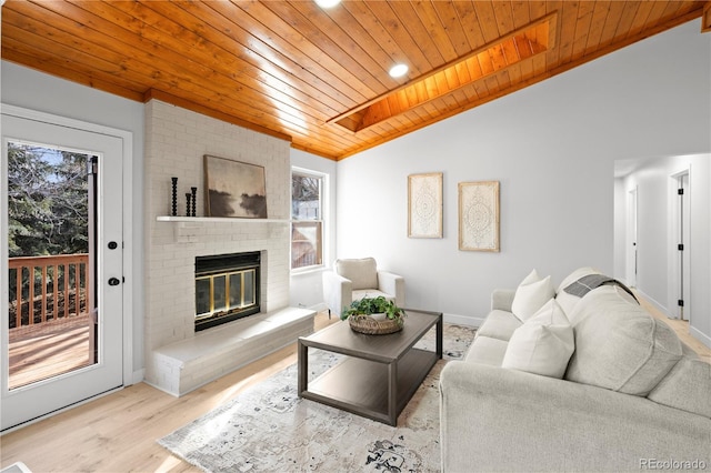 living room with a brick fireplace, wooden ceiling, light hardwood / wood-style flooring, and lofted ceiling with skylight