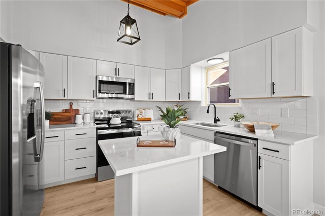 kitchen featuring a high ceiling, white cabinets, sink, a kitchen island, and stainless steel appliances