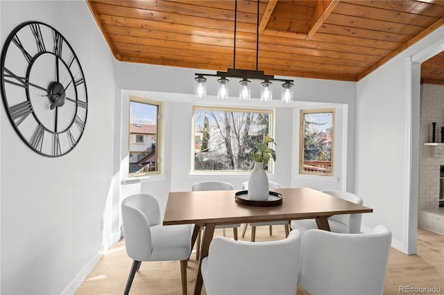 dining space featuring a brick fireplace, wooden ceiling, and light hardwood / wood-style floors