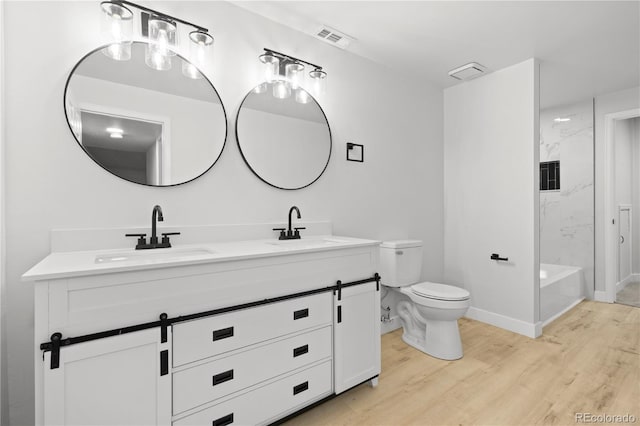 bathroom with vanity, toilet, wood-type flooring, and tiled shower