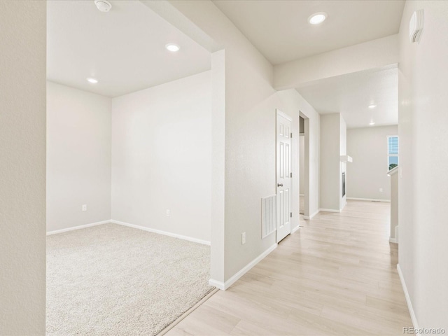 hall with baseboards, visible vents, and light wood-type flooring