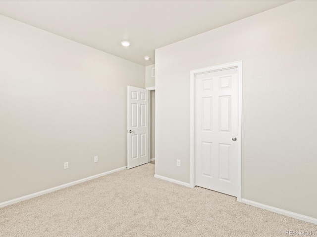 spare room featuring light colored carpet and baseboards