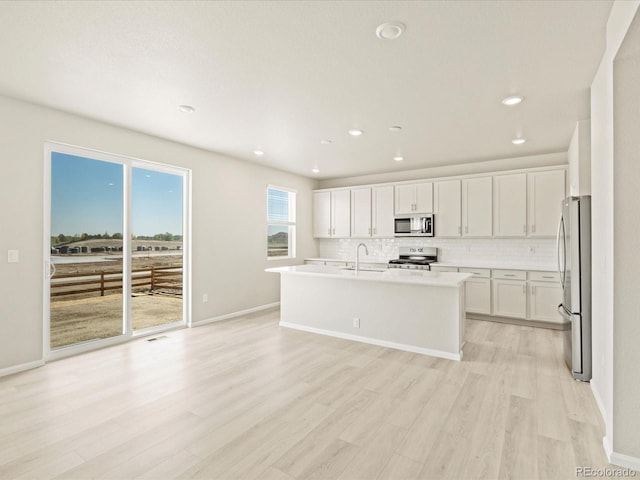 kitchen featuring stainless steel appliances, a sink, light wood-type flooring, decorative backsplash, and white cabinetry