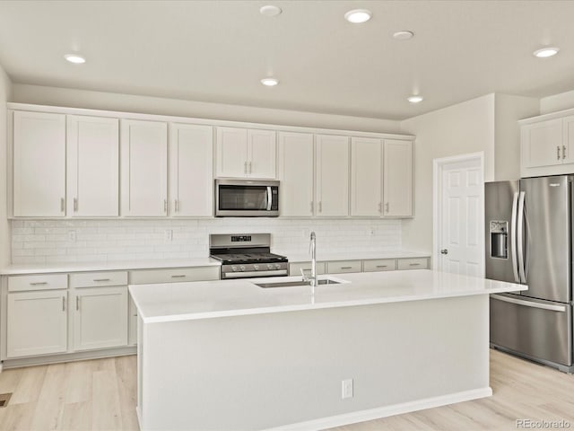 kitchen featuring light wood-type flooring, light countertops, a sink, and appliances with stainless steel finishes