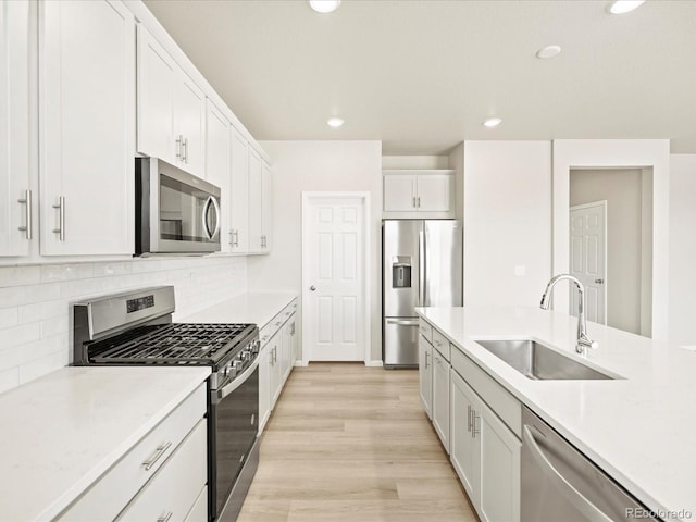 kitchen with stainless steel appliances, light countertops, a sink, and white cabinetry