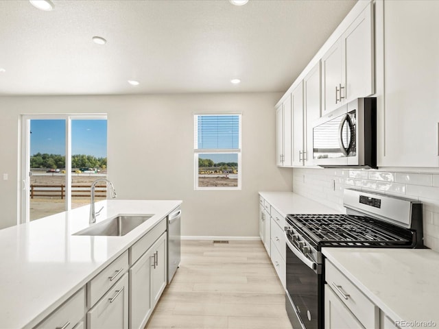 kitchen with a sink, decorative backsplash, stainless steel appliances, light countertops, and baseboards
