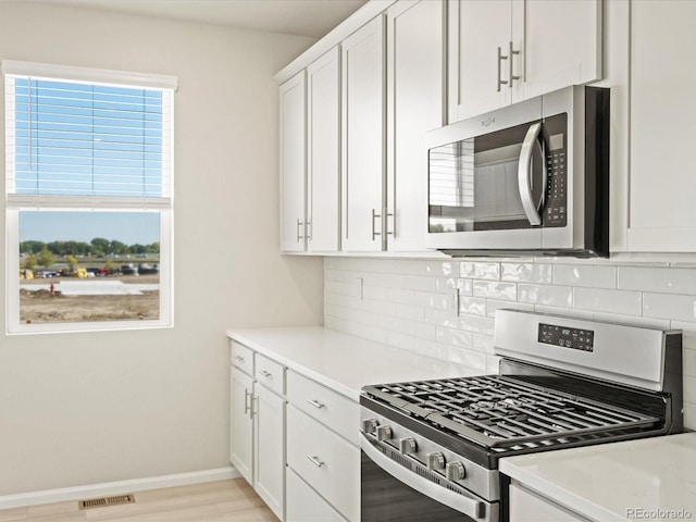 kitchen featuring white cabinets, tasteful backsplash, visible vents, light countertops, and appliances with stainless steel finishes