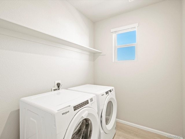 clothes washing area with washer and dryer, baseboards, light wood-style floors, and laundry area
