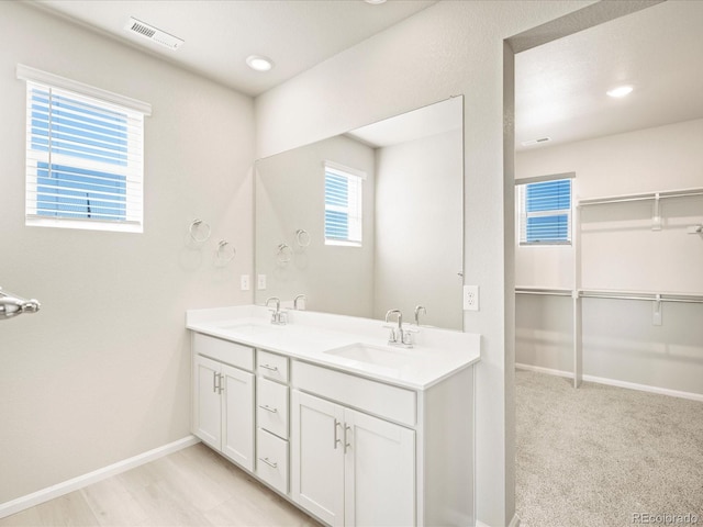 full bath featuring double vanity, visible vents, baseboards, and a sink