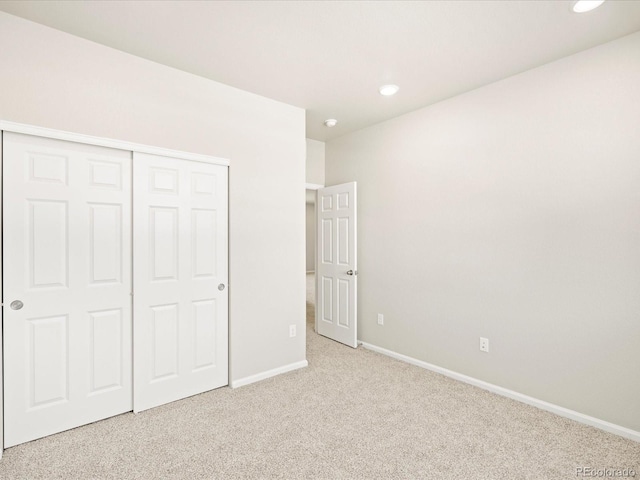 unfurnished bedroom featuring baseboards, carpet, recessed lighting, and a closet